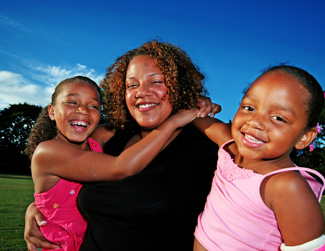 an image of a black woman and her two young girls smiling for a photograph